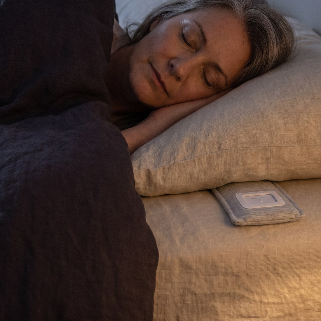 A woman asleep, the speaker in its sleeve beside her pillow