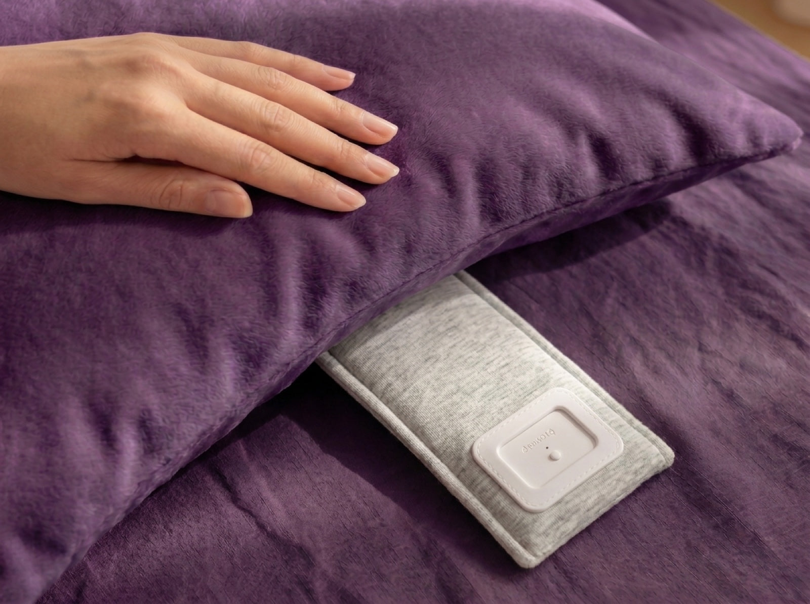 A hand sliding the Drowsie V3 flat beneath a pillow